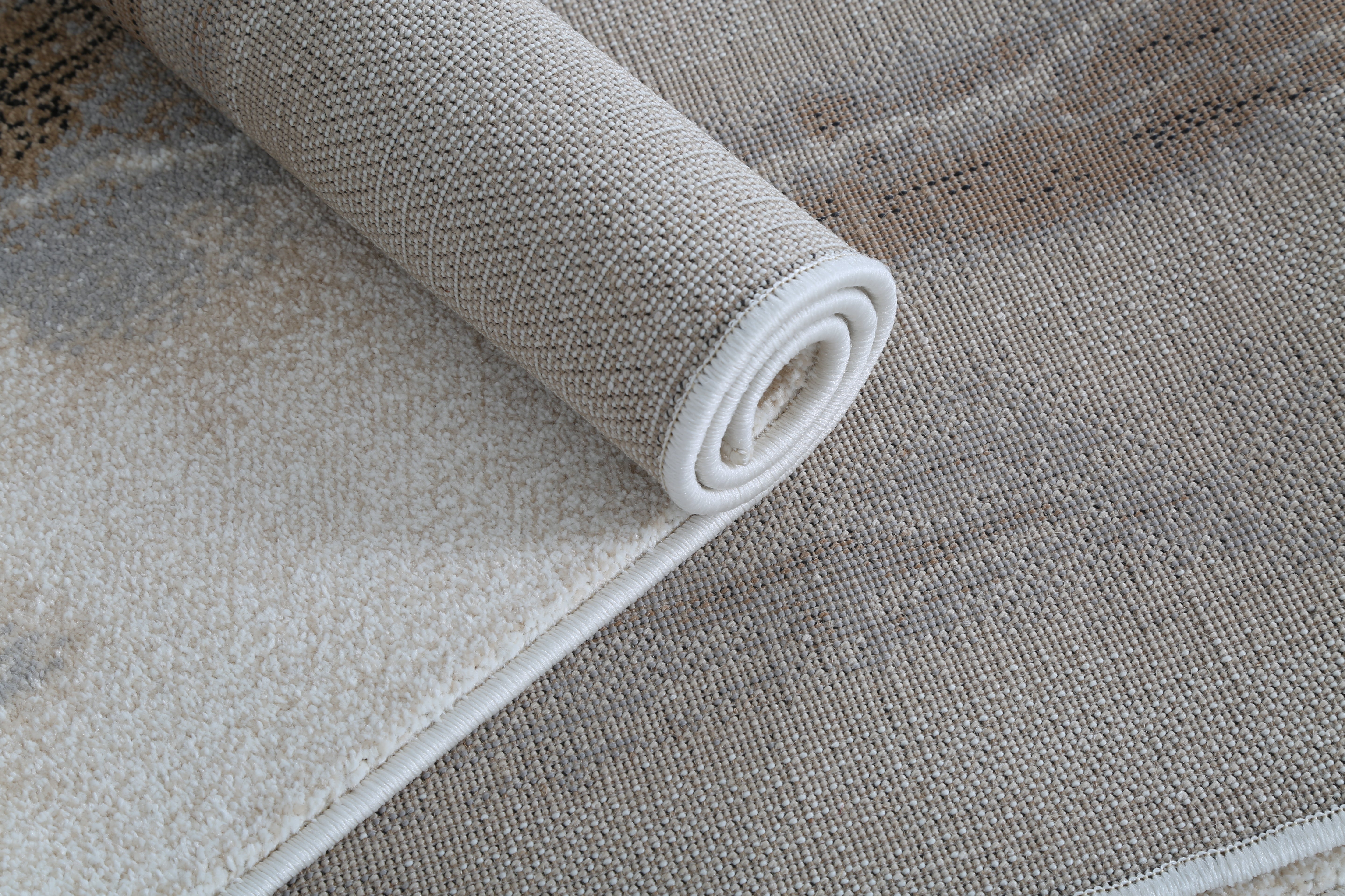 Rolled-up beige carpet on a textured surface