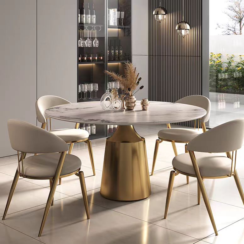 Dining room with a round marble table and gold legs, surrounded by matching chairs.