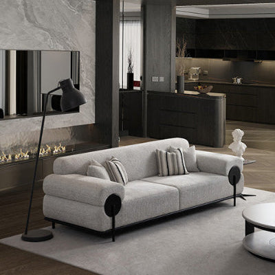 Modern living room with a gray sofa, floor lamp, and kitchen in the background.