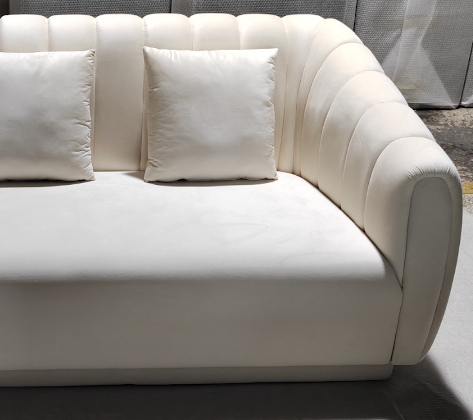 White sectional sofa with cushions on a dark floor.