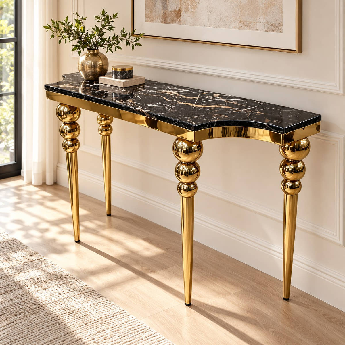Black marble console table with gold-tone sphere-detail legs styled in a room.