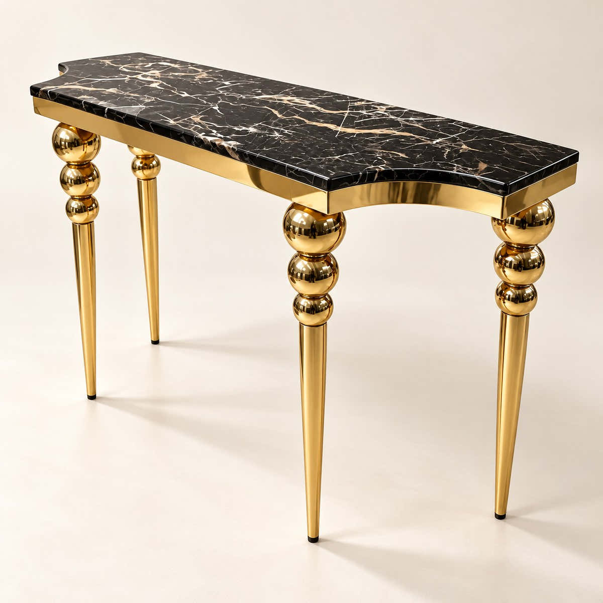 Black marble console table with gold-tone sphere-detail legs on a neutral background.