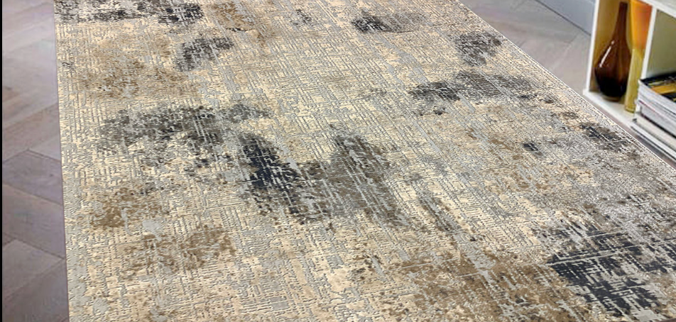 A rectangular area rug with an abstract distressed pattern in beige, gray, and black, shown on a light wood floor next to a white shelf.