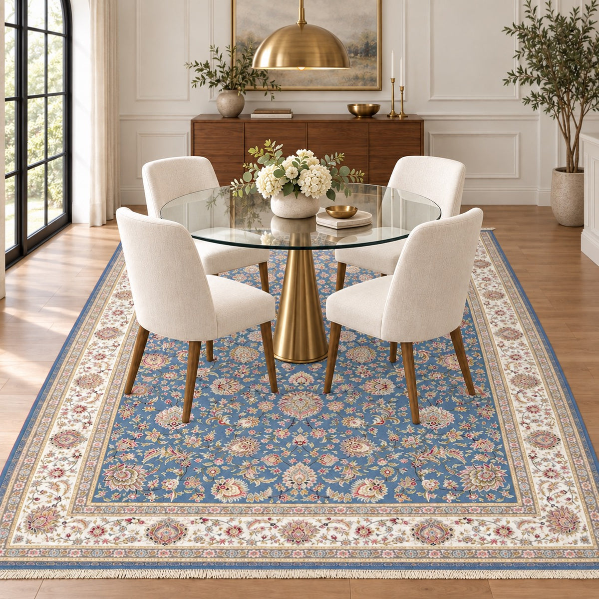 Parimah blue Persian rug with an ivory floral border and fine ivory fringe beneath a centred glass dining table in a digitally staged dining room