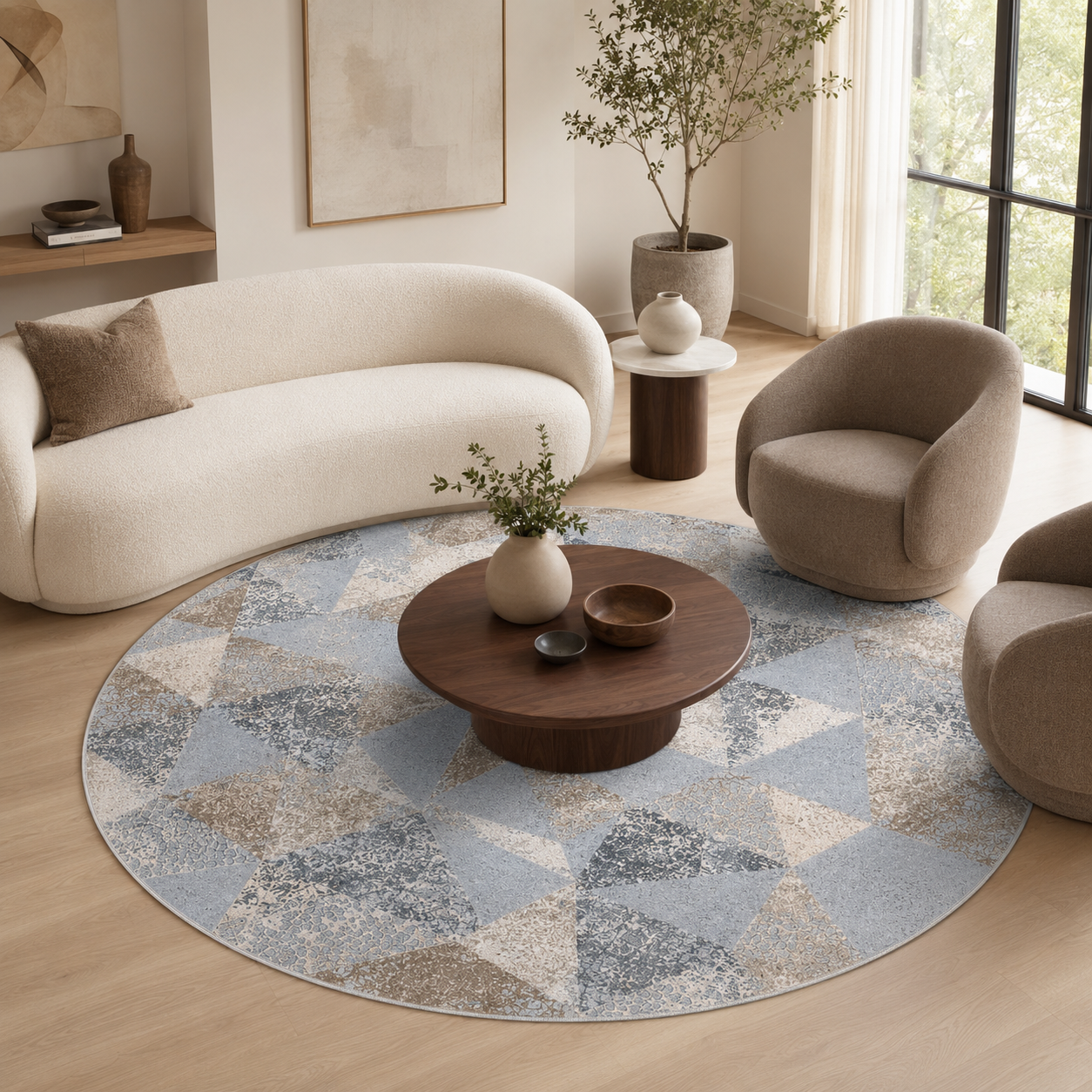 A round area rug with a geometric pattern in light blue, beige, and gray, styled in a modern living room with a cream boucle sofa, two beige armchairs, and a dark wood coffee table.