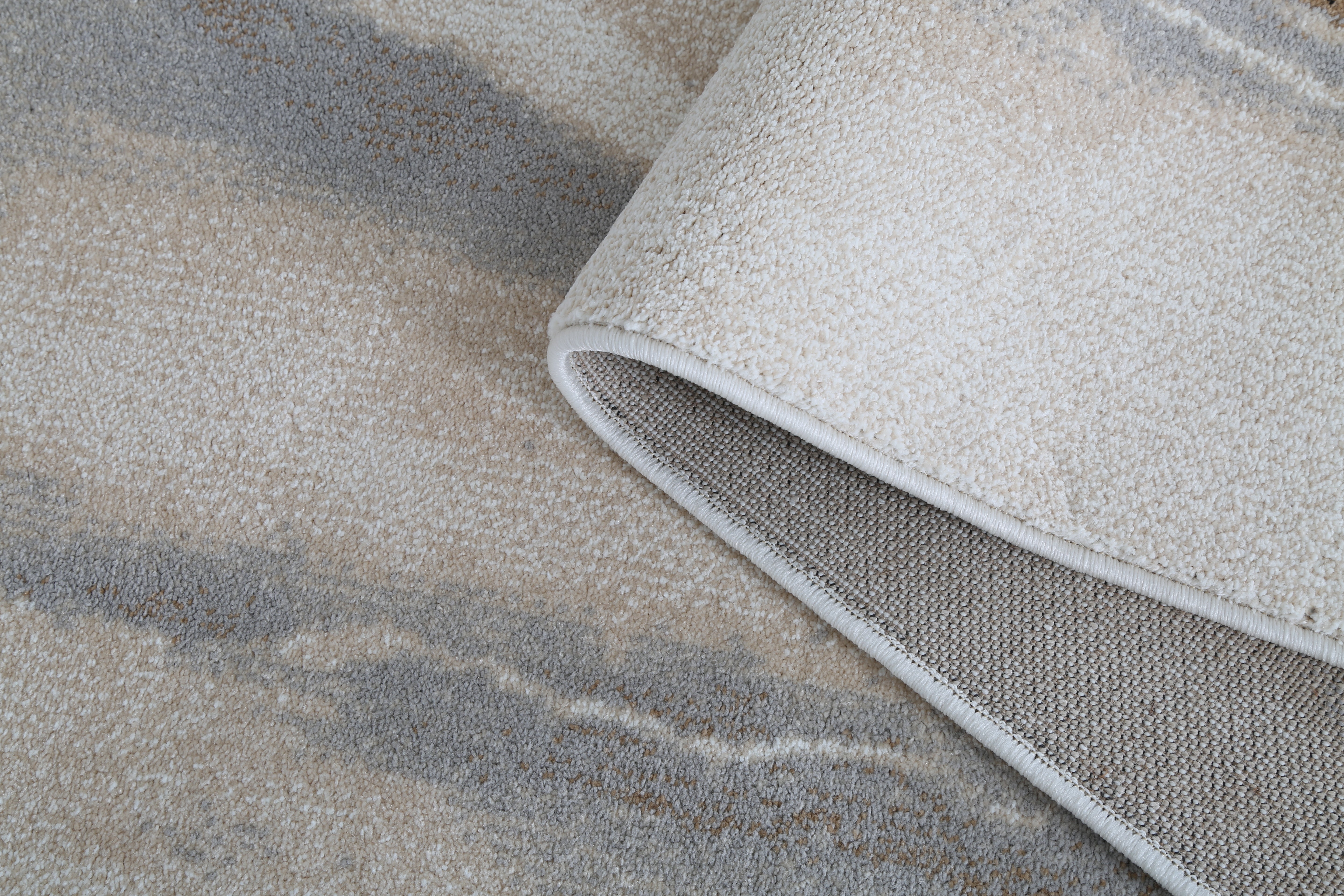 Close-up of a textured gray rug corner on a stone surface