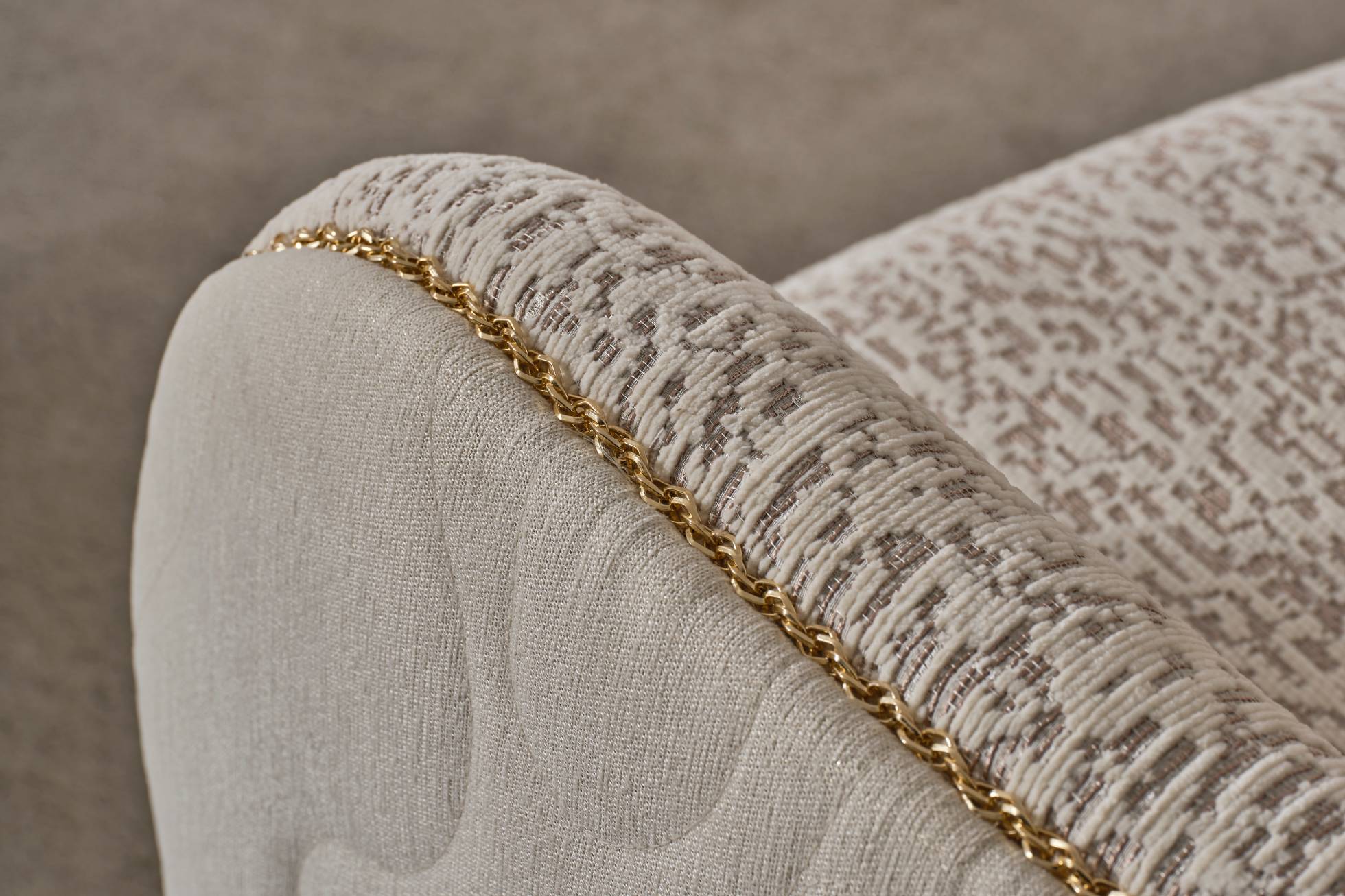 Close-up of a textured fabric surface with a gold trim on a neutral background