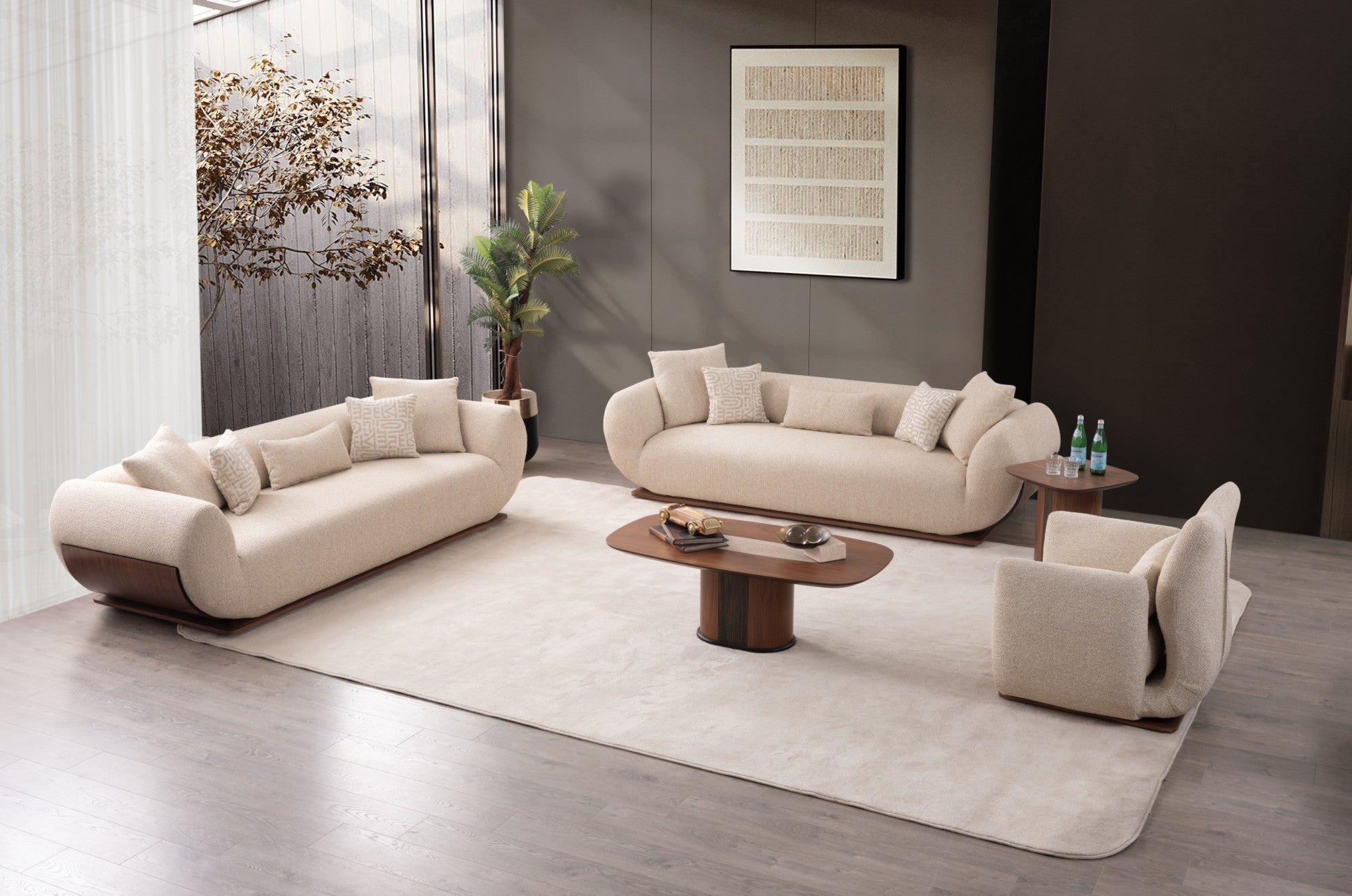 A modern living room set featuring a cream-colored curved sofa, matching armchair, and a smaller loveseat arranged around a low wooden coffee table on a large cream rug. The room has dark gray walls, a potted plant, and a window with sheer curtains.