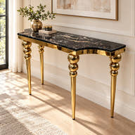 Black marble console table with gold-tone sphere-detail legs styled in a room.
