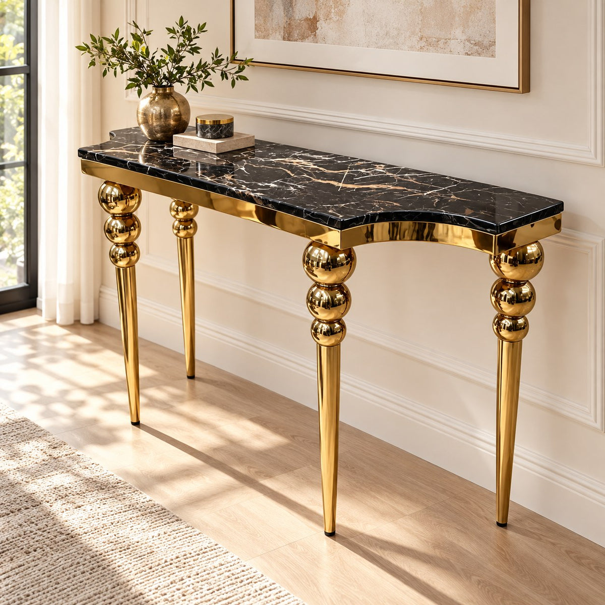 Black marble console table with gold-tone sphere-detail legs styled in a room.