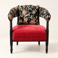 Red and black floral accent chair with dark sculptural frame on a neutral background.