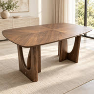 Wood-veneer dining table with rounded top and open-cutout supports styled in a room.