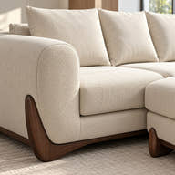 Cream-colored textured bouclé sectional sofa with dark wood legs, shown in a bright, modern room setting.