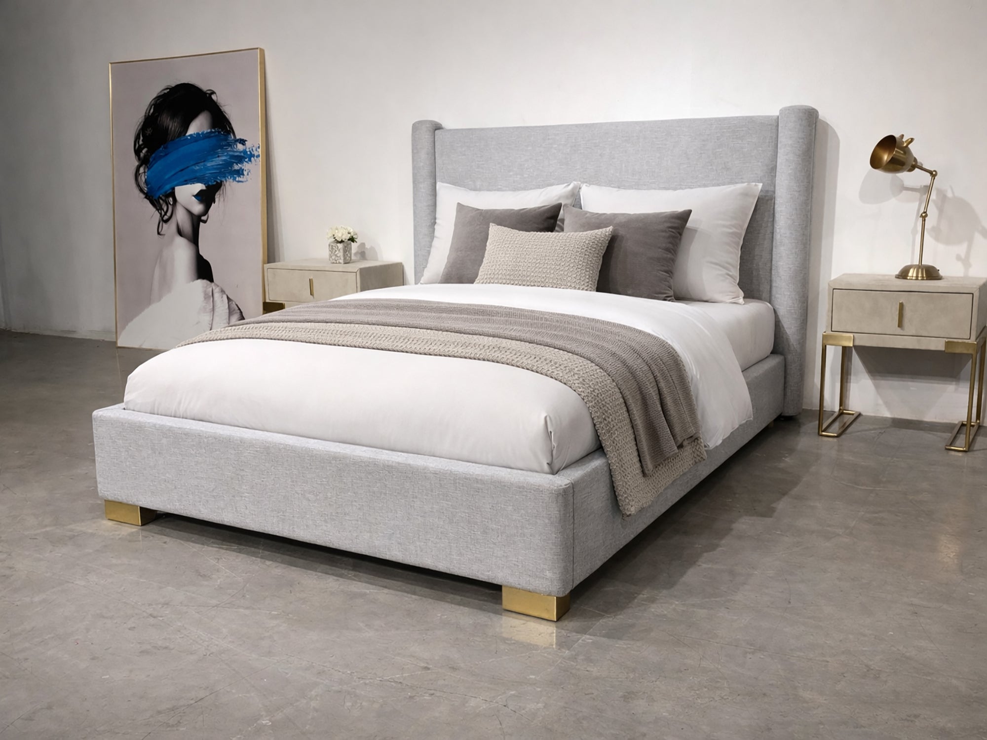 Gray upholstered bed with white bedding in a minimalistic bedroom setting.